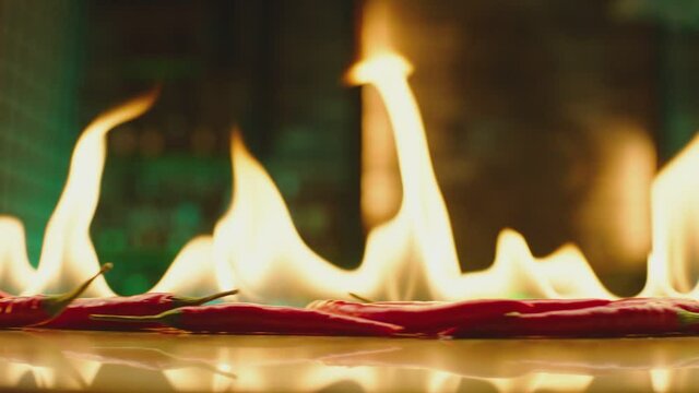 Close up shot of burning Red Chilli Peppers on table . Hot red chili peppers in flames on a restaurant background . Closeup , Slow Motion 