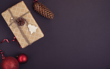 Christmas gift wrapped in craft paper and Christmas decoration on a dark background. Flat lay. 
