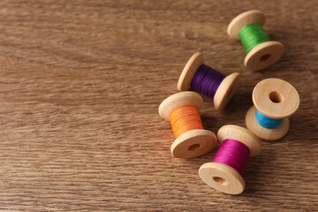 Set of color sewing threads on wooden table, space for text