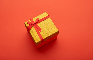 Red and gold gift box on a bright red background. 