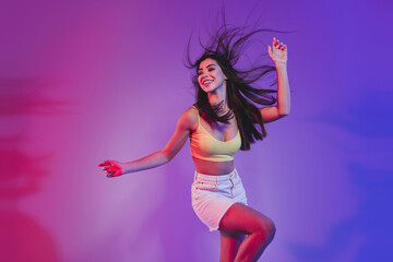 Portrait of gorgeous cheery dreamy girl dancing having fun isolated over vivid violet purple neon color background