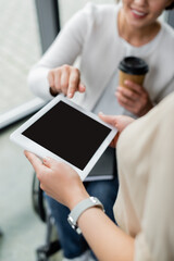 cropped view of blurred businesswoman with disability pointing at digital tablet with blank screen in hands of colleague