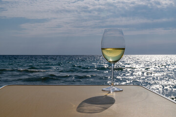 Romantic glass of white wine, on the sea beach. Wine tasting and relaxation at the resort
