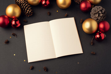 An open diary (notebook) among Christmas balls and cones. New year goals concept.