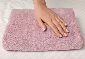 Woman touching soft towel on bed, closeup