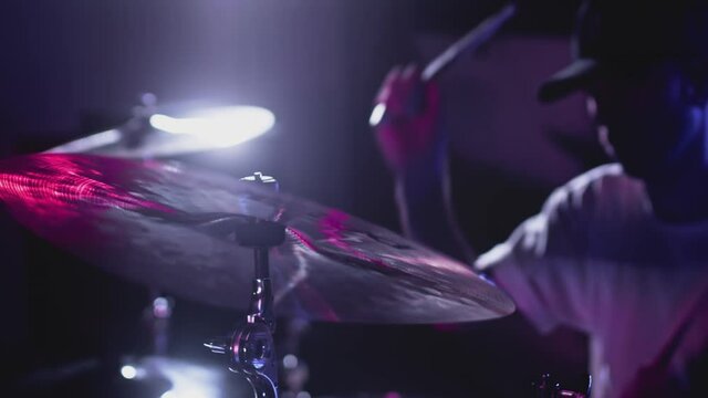 Male Artist hits the drum kit, snare drum and crash. Night show in a musical instrument recording studio. The drummer on the Repetition of rock or metal music band. Musical party. Slow motion