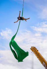 Aerial silk performance from yellow crane outdoor, Man dancing acrobatic on a sky background,...