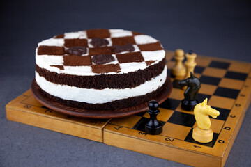 Sponge cake with butter cream. Cake in the form of a chessboard. A gift for the day of a chess player. Cake with chocolate cakes and white pudding.