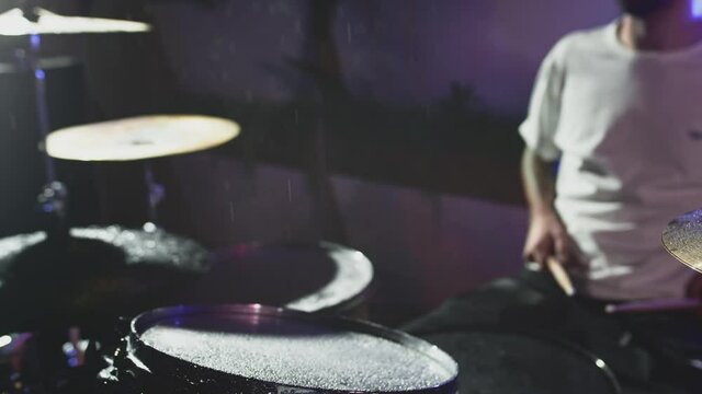 Water droplets from hitting the drum fly into slow motion, crash, ride and snare drum. Night show in a musical instrument recording studio. The drummer knocks and beats, Repetition of rock music band