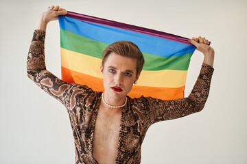 Womanlike man posing with rainbow flag while celebrating gay pride festival event