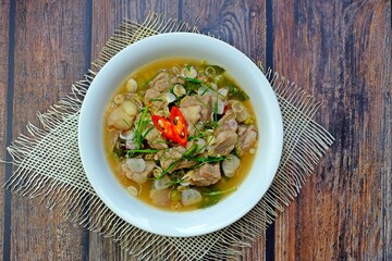 Cartilage pork curry seasoned with fermented shrimp paste chili sauce (Run Juan Curry, Gaaeng ranjuaan) in white bowl on wooden table. Authentic royal Thai cuisine.