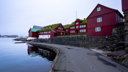View of the beautiful city of Torshavan in the Faroe Islands Governments colorful red building  with grass on the roof , and marina