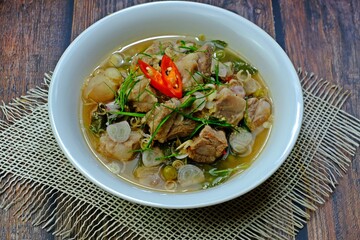 Cartilage pork curry seasoned with fermented shrimp paste chili sauce (Run Juan Curry, Gaaeng ranjuaan) in white bowl on wooden table. Authentic royal Thai cuisine.