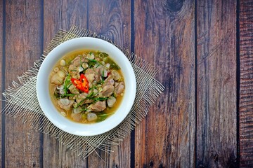 Cartilage pork curry seasoned with fermented shrimp paste chili sauce (Run Juan Curry, Gaaeng ranjuaan) in white bowl on wooden table. Authentic royal Thai cuisine.
