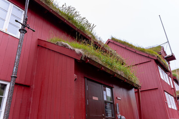 View of the beautiful city of Torshavan in the Faroe Islands Governments colorful red building  with grass on the roof , and marina