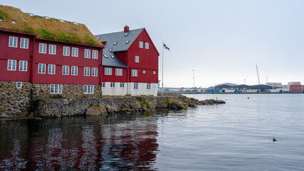 Obraz premium View of the beautiful Faroe Islands Flag in the city of Torshavan in the Governments red building with grass on the roof