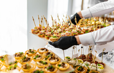 woman hands of a waiter prepare food for a buffet table in a restaurant