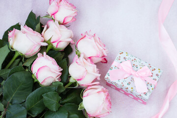 on a pink background a bouquet of pink roses and a box with a gift