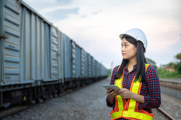 Women engineer railway wearing safety uniform holding tablet for inspection and check container...