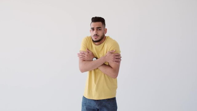 Young man shivering with cold over white background