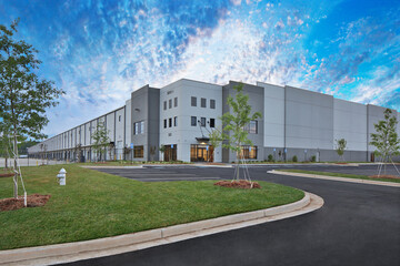 Fototapeta na wymiar Modern gray warehouse distribution facility under gorgeous cloudy sky