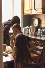 Candid asian family mother and two daughters in kitchen at home in backlight, cozy apartment lifestyle, selective focus
