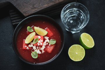 Bowl of gazpacho cold soup made of watermelon, top view on a black stone background, horizontal shot