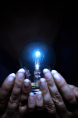 hands holding a light bulb, electric energy and ideas concept