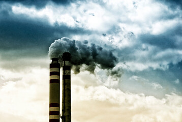 chimneys with smoke from an industrial plant, climate change induced by human activity and global warming concept