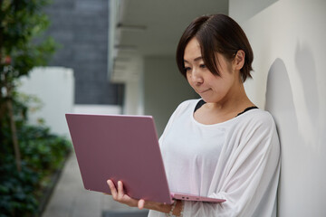 オフィスでノートパソコンを持ちながら仕事をする日本人女性