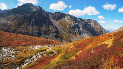 Panoramic view of stone riverbed in the autumn Alpine highlands. The riverbed without water, the drought at the autumn. The riverbed is paved with stones.