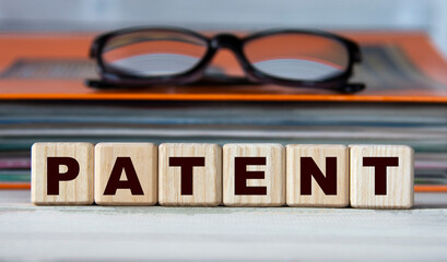 PATENT - word on wooden cubes on the background of a folder with documents and glasses