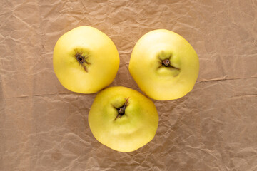 Three ripe organic quince on craft paper, close-up, top view.