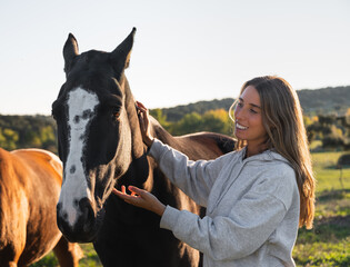 Obraz premium Young woman with her horse in evening sunset light