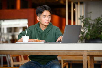 カフェでパソコン作業をする若者