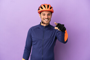 Young Brazilian cyclist man isolated on purple background surprised and pointing front - obrazy, fototapety, plakaty