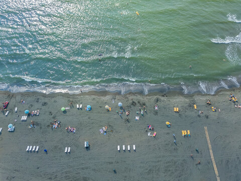 Drone view of the beach with vacationers on the black magnetic sands in Georgia. Aerial photography, black sand beach, waves, island, lifestyle, people. Coastline