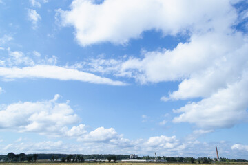 white fluffy different size block in the blue sky.. from below you can see a small village