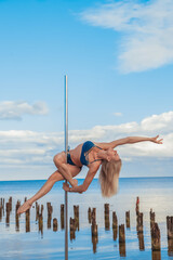 Woman blonde long hair beautiful body on a pylon sportswoman at the sea