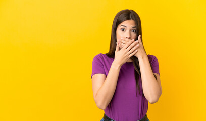 Teenager Brazilian girl over isolated yellow background covering mouth with hands