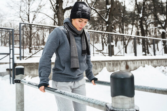 Athletic woman during her winter outdoor workout on parallel bars