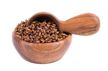 Cassia tora beans in wooden bowl and spoon, isolated on white background. Sicklepod or Senna obtusifolia. Clipping path.