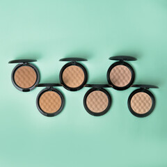 Multiple blush and compact face powders on a delicate blue background. Pastel trendy colors matte foundation