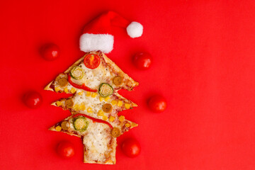 Delicious vegetarian Christmas tree pizza with tomatoes, vegetables and cheese on red background. Creative, funny food concept for kids. Top view, flat lay. Copy space. 