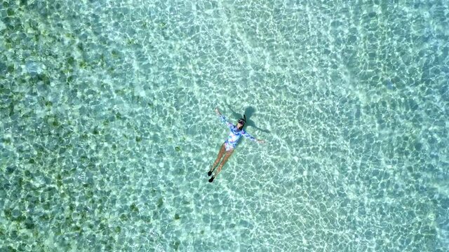 Top down view of a girl floating in a lagoon