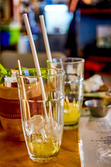 2 glasses with ice and leftover lemonade or other yellow drink are on the table with straws inside.
