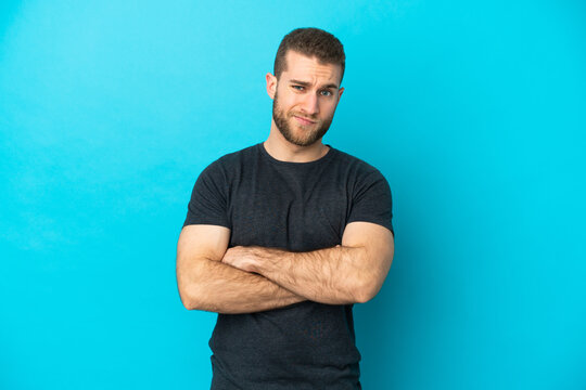 Young handsome caucasian man isolated on blue background feeling upset