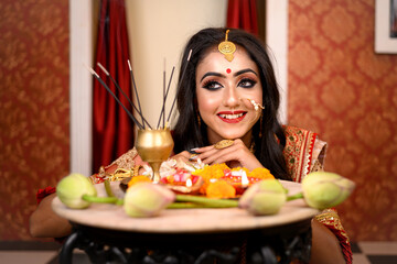 Portrait of pretty young Indian woman wearing traditional saree, gold jewellery and bangles, smiles...
