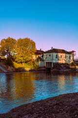 Obraz premium Reflection of the home and golden trees in the river water.