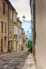 Fototapeta na wymiar Summer city landscape - view of a medieval street in a provincial French town, in the historical province Gascony, the region of Occitanie of southwestern France